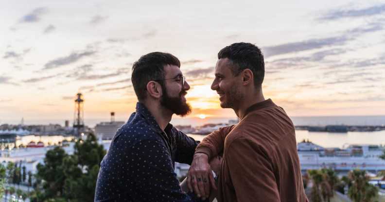 Gay couple on lookout above the city with view to the port, Barcelona, Spain.