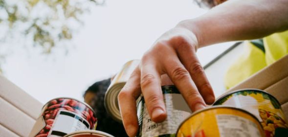 A person stacking tin cans at a food bank.
