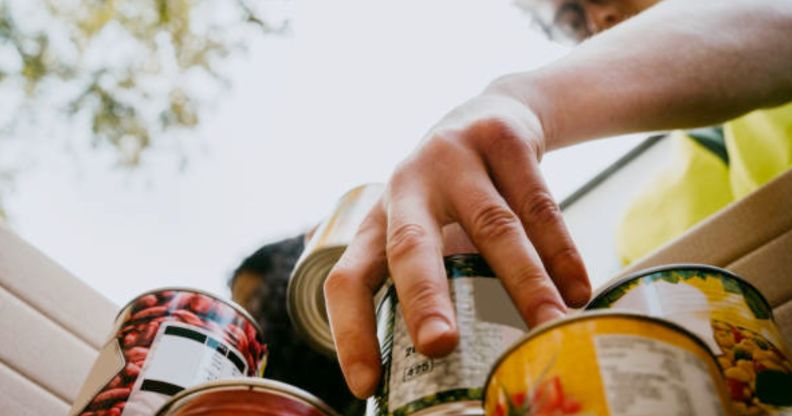 A person stacking tin cans at a food bank.