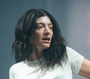 Lorde performs during day three of Glastonbury festival. she'll looking off in a white t-shirt with two silver chains.