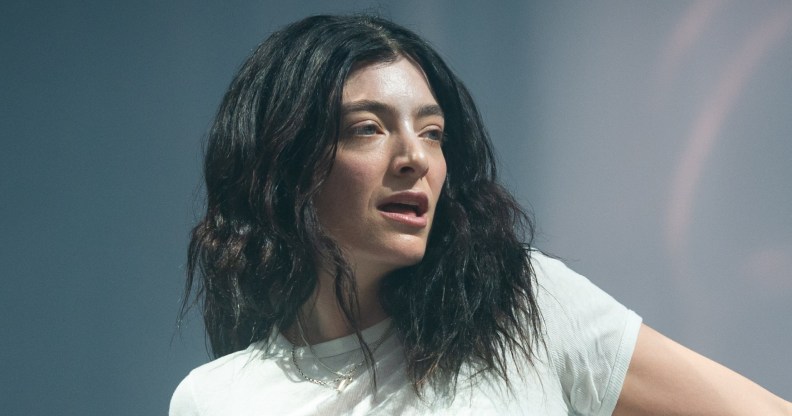 Lorde performs during day three of Glastonbury festival. she'll looking off in a white t-shirt with two silver chains.