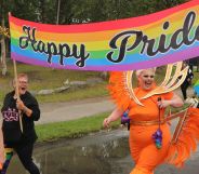 A photo from Senja Pride featuring smiling participants and drag queens holding a banner that says Happy Pride.