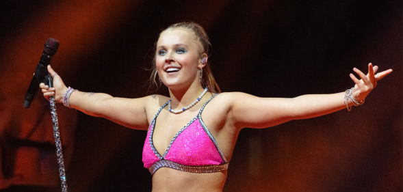 JoJo Siwa on stage in London in a pink sparkly top.