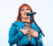 CMAT performs in a blue laced up top and places her hands to her chest as she looks off to the right.