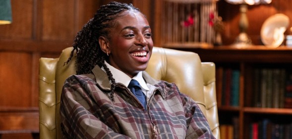 Cat Burns wearing a white shirt, blue tie and a brown chequered jacet on The Celebrity Traitors