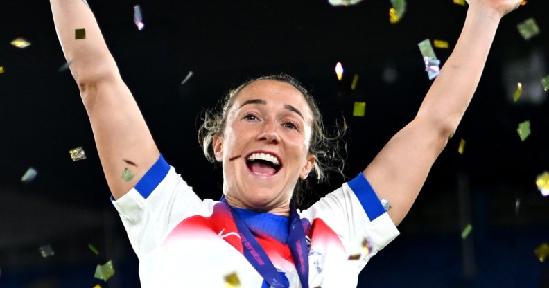 Lucy Bronze of England celebrates with her arms in the air and golden confetti around her