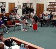 Three activists stood up and began to strip as Nick Blanchard continued to speak.