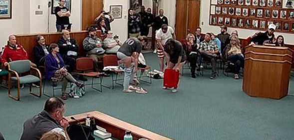 Three activists stood up and began to strip as Nick Blanchard continued to speak.