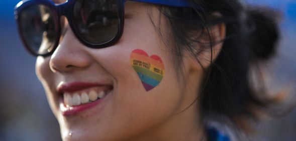 A smiling woman with a Pride heart on her cheek.