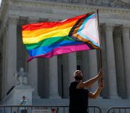 Someone holding an LGBTQ+ flag outside the Supreme Court.