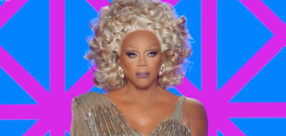 RuPaul in a gold shiny dress on the judging panel of Drag Race UK season 7.