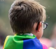 A child with a Pride flag on their shoulders.