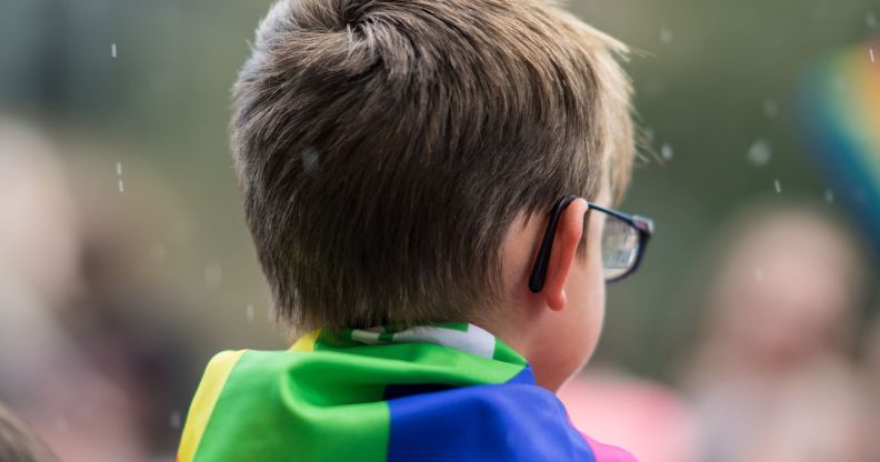 A child with a Pride flag on their shoulders.