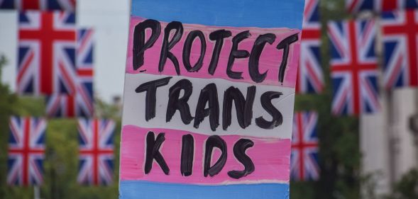 A sign reading "protect trans kids" surrounded by banners of the Union Jack.