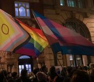 A group of protestors holding LGBTQ+ Pride flags.