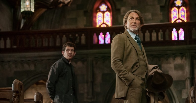 Wake Up Dead Man Josh O'Connor standing behind Daniel Craig in a church.