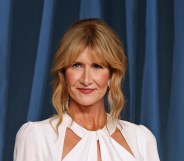 Laura Dern against a blue curtain background wearing a white dress.