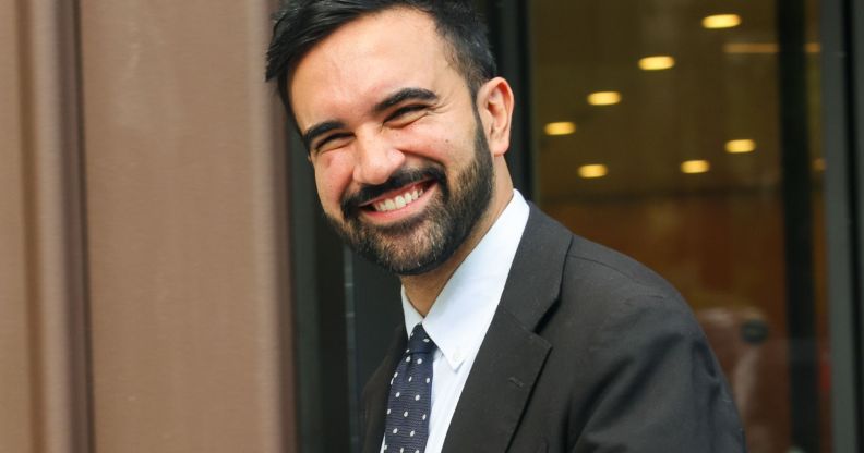 Zohran Mamdani smiling while walking through the streets of NYC.