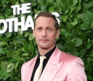 Alexander Skarsgård attends the 35th Gotham Film Awards. He's wearing a pink suit, black shirt and cream tie
