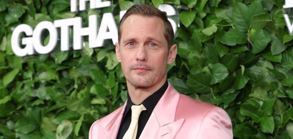 Alexander Skarsgård attends the 35th Gotham Film Awards. He's wearing a pink suit, black shirt and cream tie
