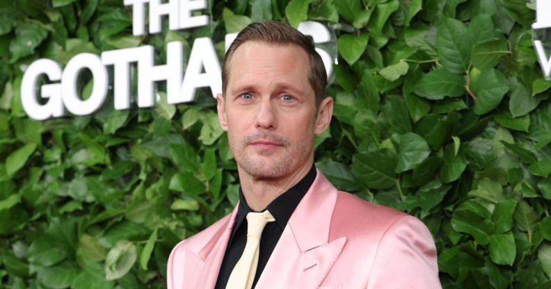 Alexander Skarsgård attends the 35th Gotham Film Awards. He's wearing a pink suit, black shirt and cream tie