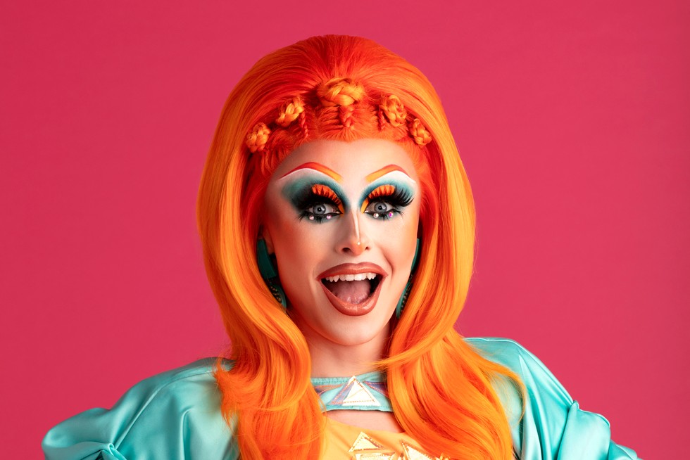 Blue hydrangea in a bright orange wig and blue dress on a pink background.