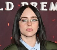Billie Eilish in small glasses, a light blue shirt and green jacket