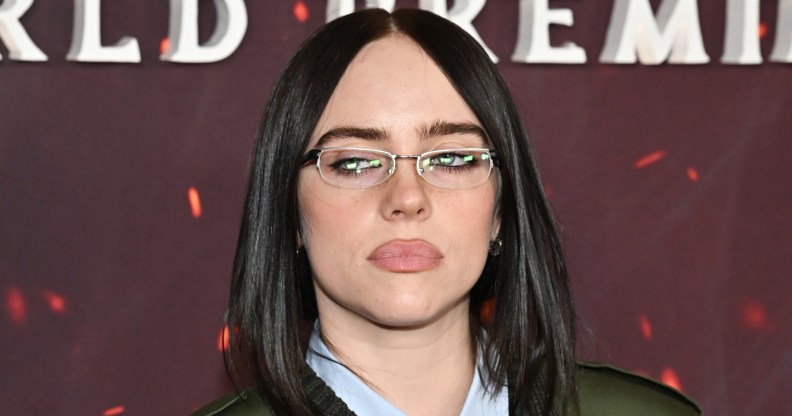 Billie Eilish in small glasses, a light blue shirt and green jacket