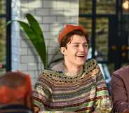 Cheerful young man wearing Christmas cracker hat playing after dinner games with family.