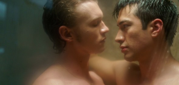 Heated Rivalry (L to R) - Connor Storrie as Ilya Rozanov and Hudson Williams as Shane Hollander. The pair are standing with their bodies pressed together in the shower.