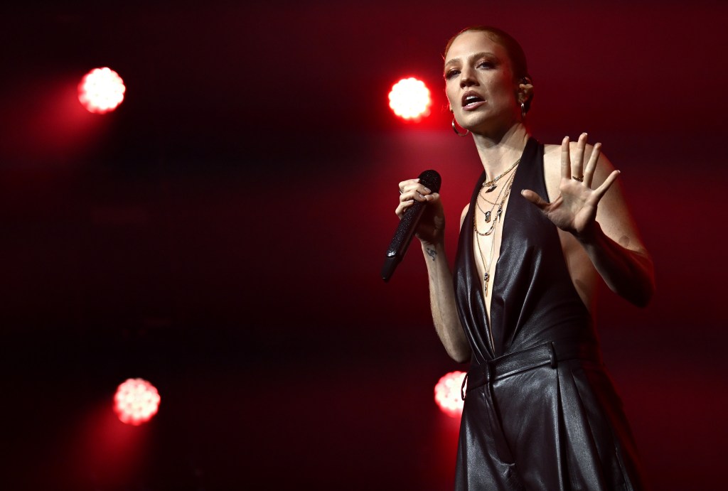 Jess Glynne on stage in an all black leather halter neck look