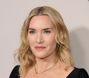 Kate Winslet looking past the camera. wearing a black top and chain necklace