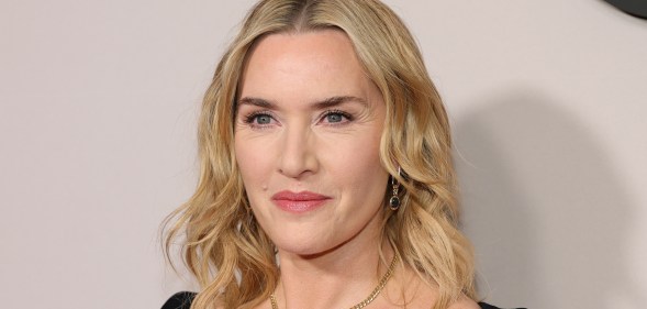 Kate Winslet looking past the camera. wearing a black top and chain necklace