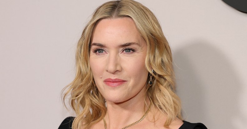 Kate Winslet looking past the camera. wearing a black top and chain necklace