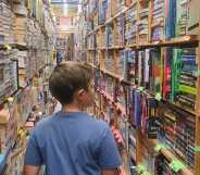 Boy walks through a library full of books.