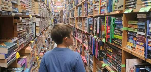 Boy walks through a library full of books.