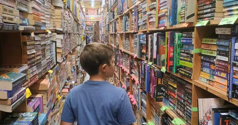 Boy walks through a library full of books.