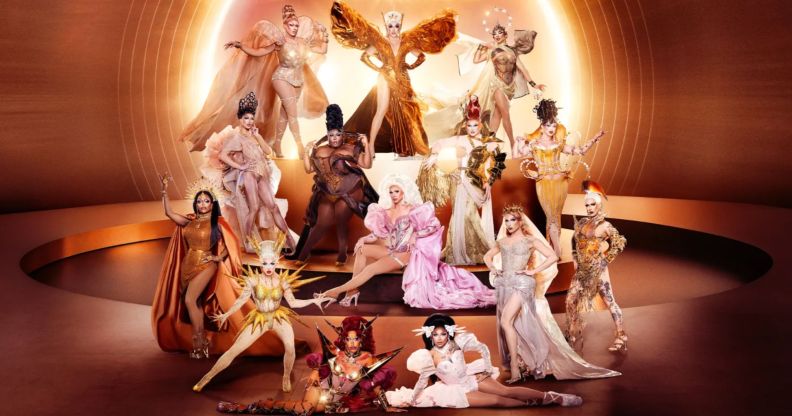 The promotional photo for Drag Race season 18 featuring 14 queens posing in various shades of gold and orange.