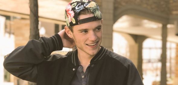 A photo of Rhett Douglas Messerly smilingin a black jacket and multicoloured cap.