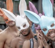 A group of shirtless men at a Pride event wearing multicoloured rabbit ears.