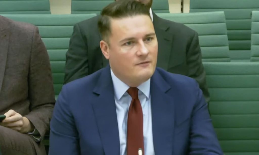 A screenshot of Wes Streeting in a blue suit and red tie sat during a House committee hearing.