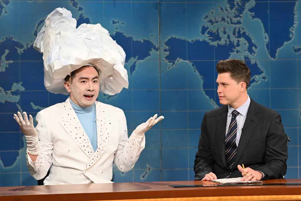 Bowen Yang dressed as a white cloud sat at the SNL news desk