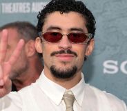 Bad Bunny at a red carpet event throwing a peace symbol.