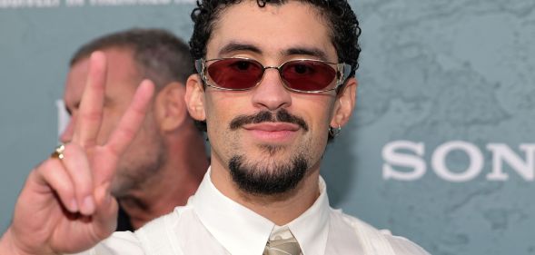 Bad Bunny at a red carpet event throwing a peace symbol.