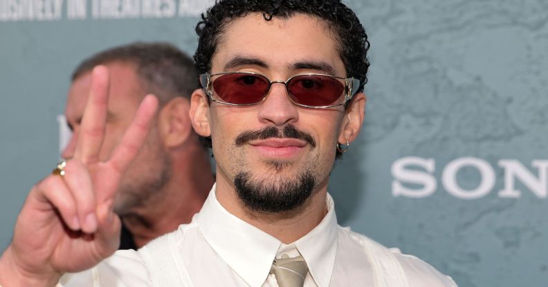 Bad Bunny at a red carpet event throwing a peace symbol.