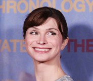 Dylan Mulvaney smiling on a light blue background