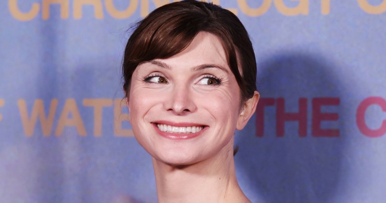 Dylan Mulvaney smiling on a light blue background