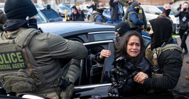 ICE agents detain a woman after pulling her from a car on 13 January, 2026 in Minneapolis, Minnesota.