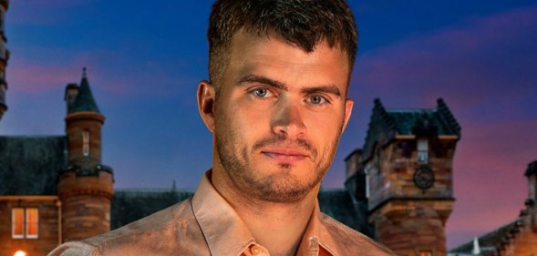 Matthew stood in front of The Traitors castle in a light pink shirt