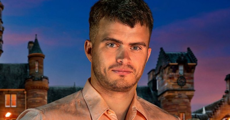 Matthew stood in front of The Traitors castle in a light pink shirt